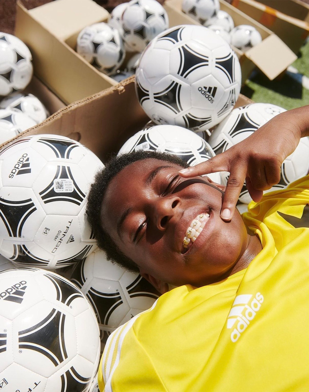 Young soccer player smiling and laying on soccer balls